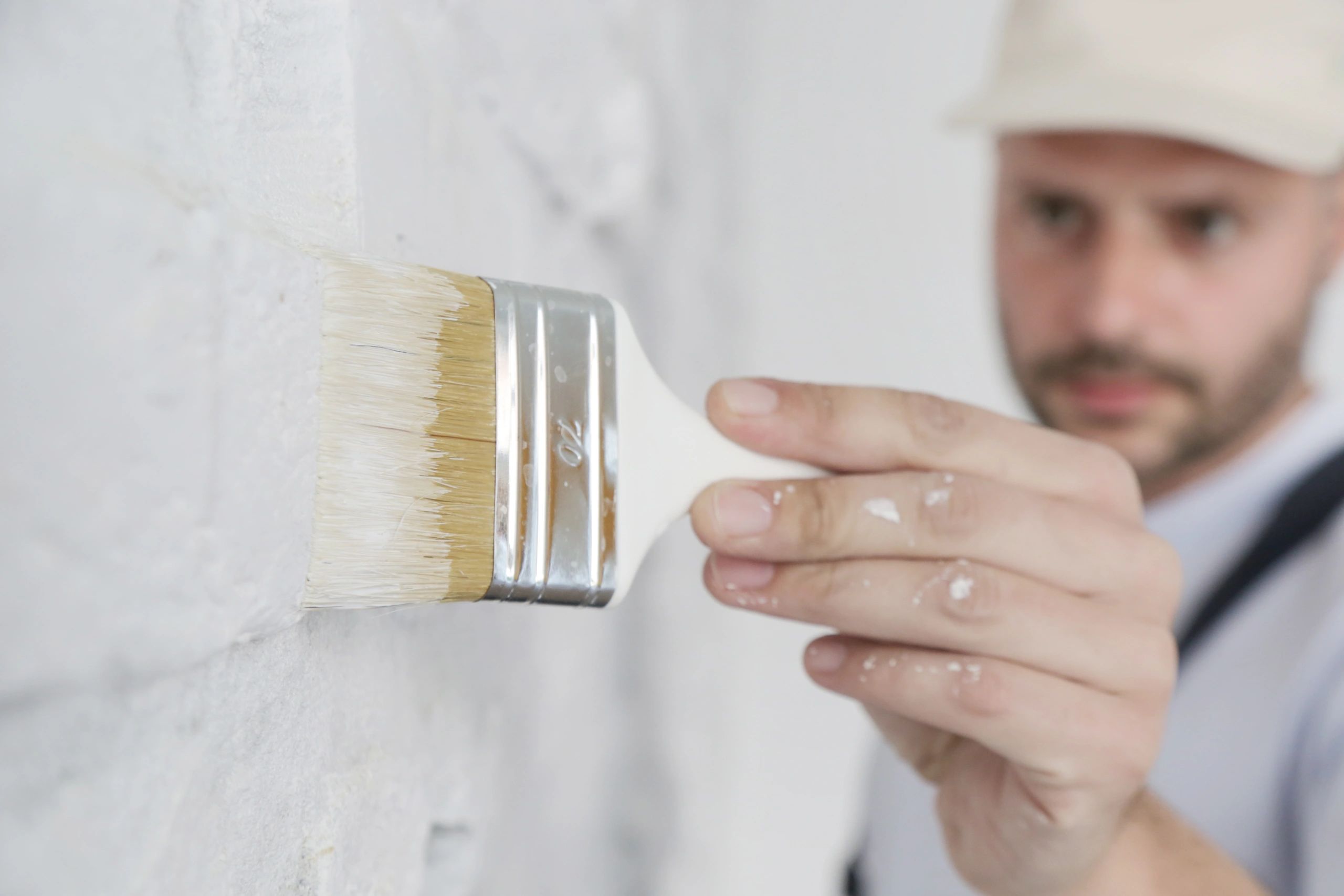 Close-up of brush painting a white brick wall
